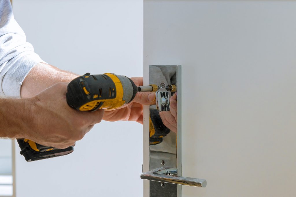 Carpenter fixing lock in door with home hand close-up.