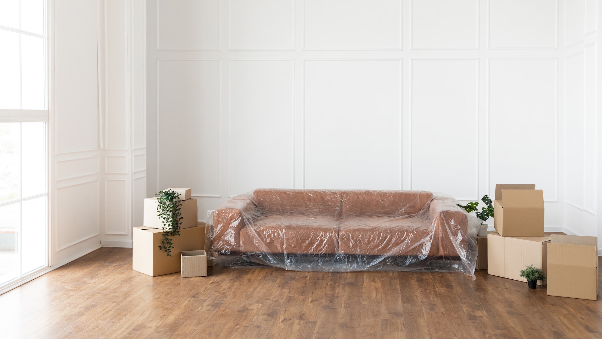 Living room with covered couch, stacks of boxes during relocation